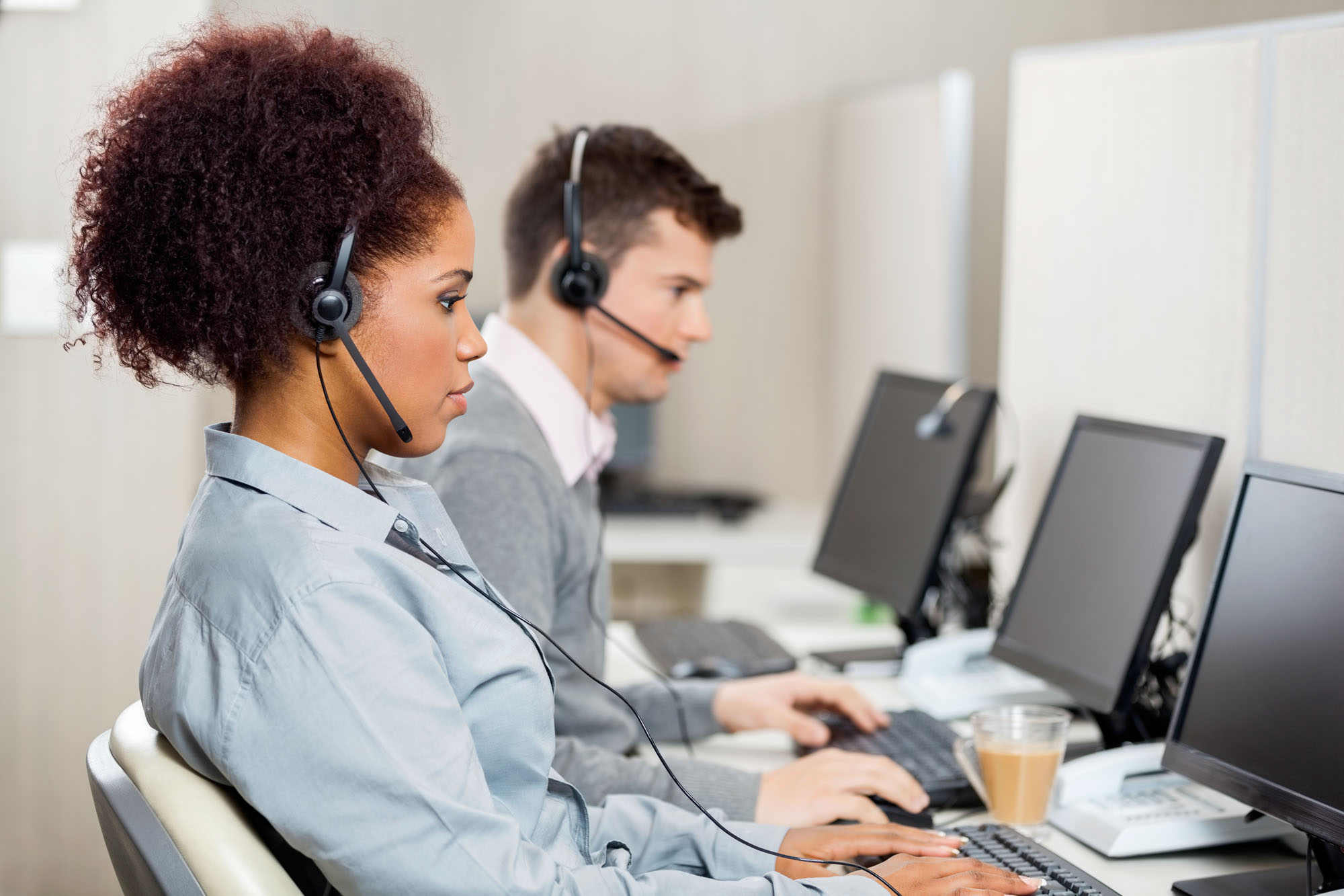 Side view of female customer service representatives with colleague working in call center