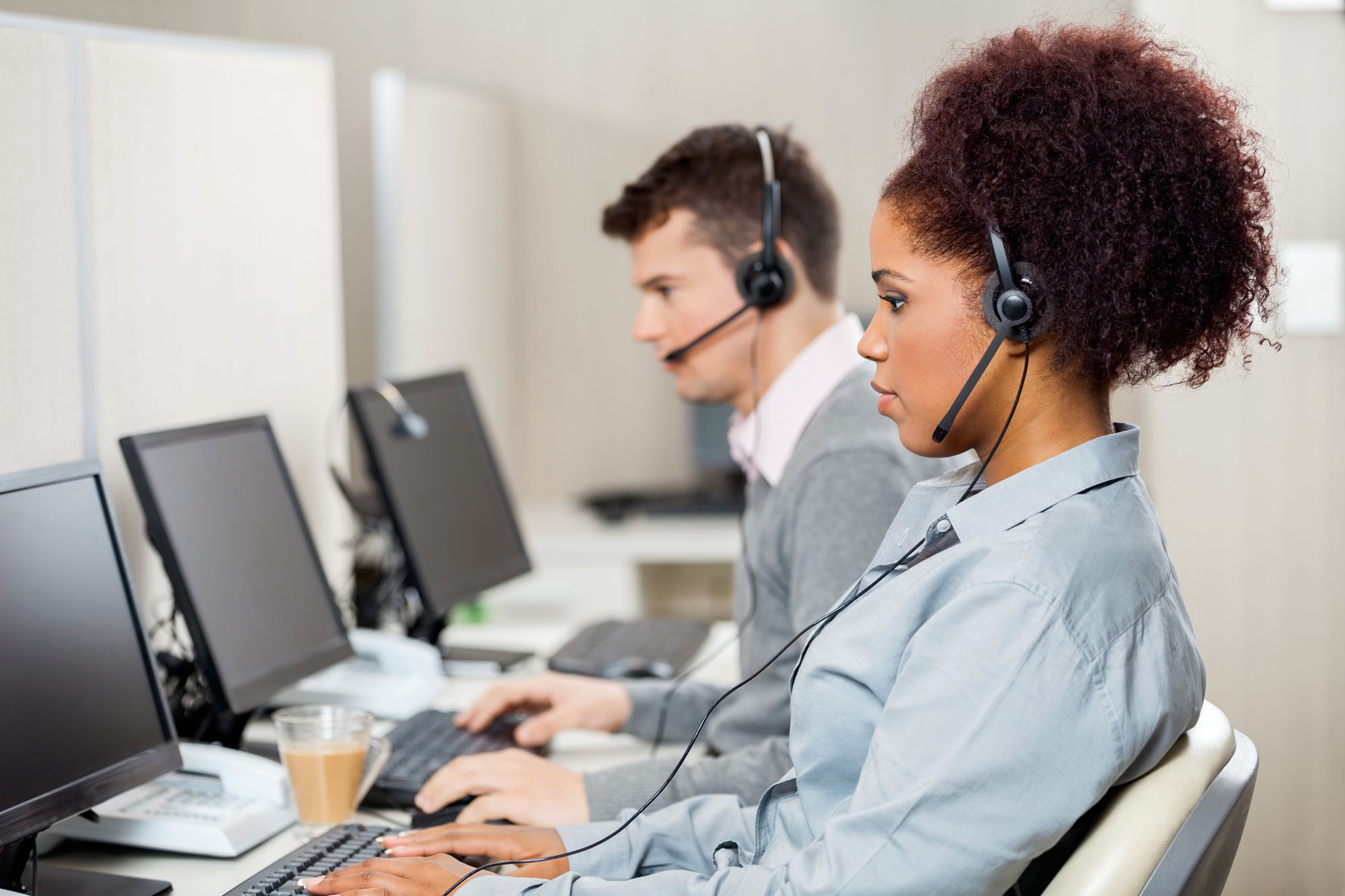 Side view of female customer service representatives with colleague working in call center